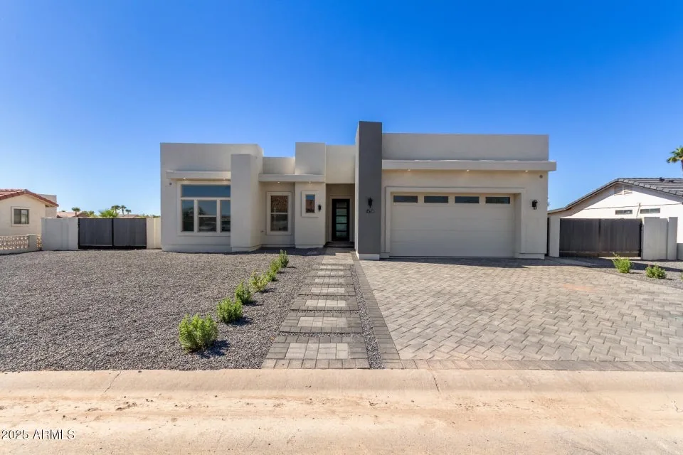 Desert Front Elevation: Low-slung desert contemporary with a three-car garage, decomposed-granite drive and clean parapet lines.