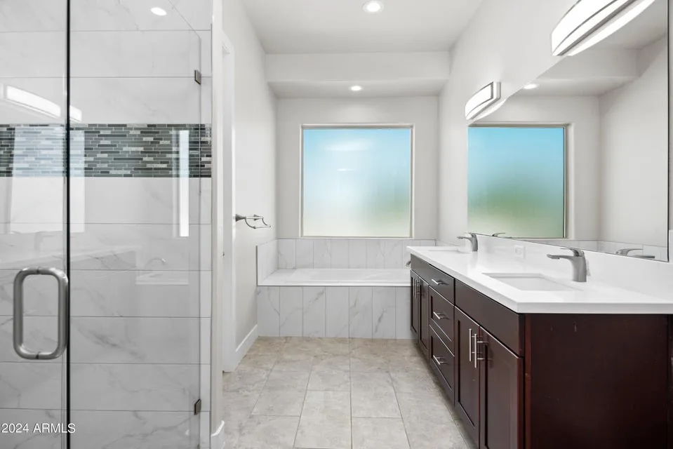 Frameless Glass Shower: Frameless enclosure alongside a drop-in tub deck, with a continuous large-format tile floor.