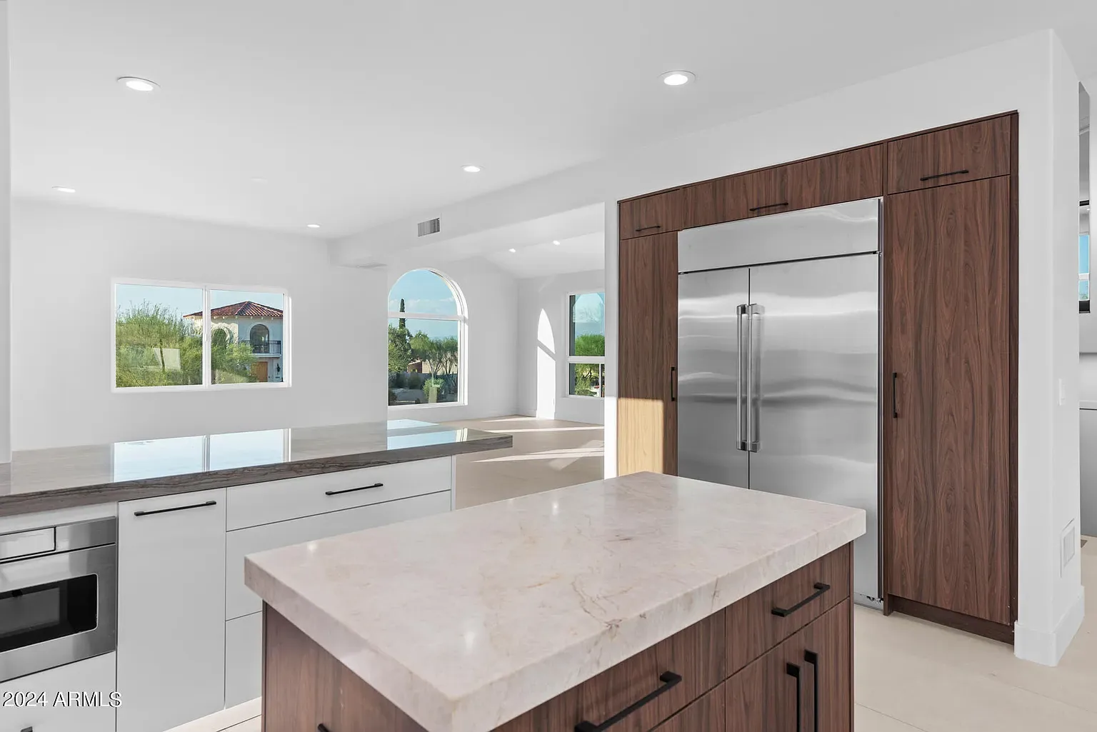 Integrated Appliance Kitchen: Panel-ready column refrigeration framed in walnut, with a marble-topped prep island and concealed pantry.