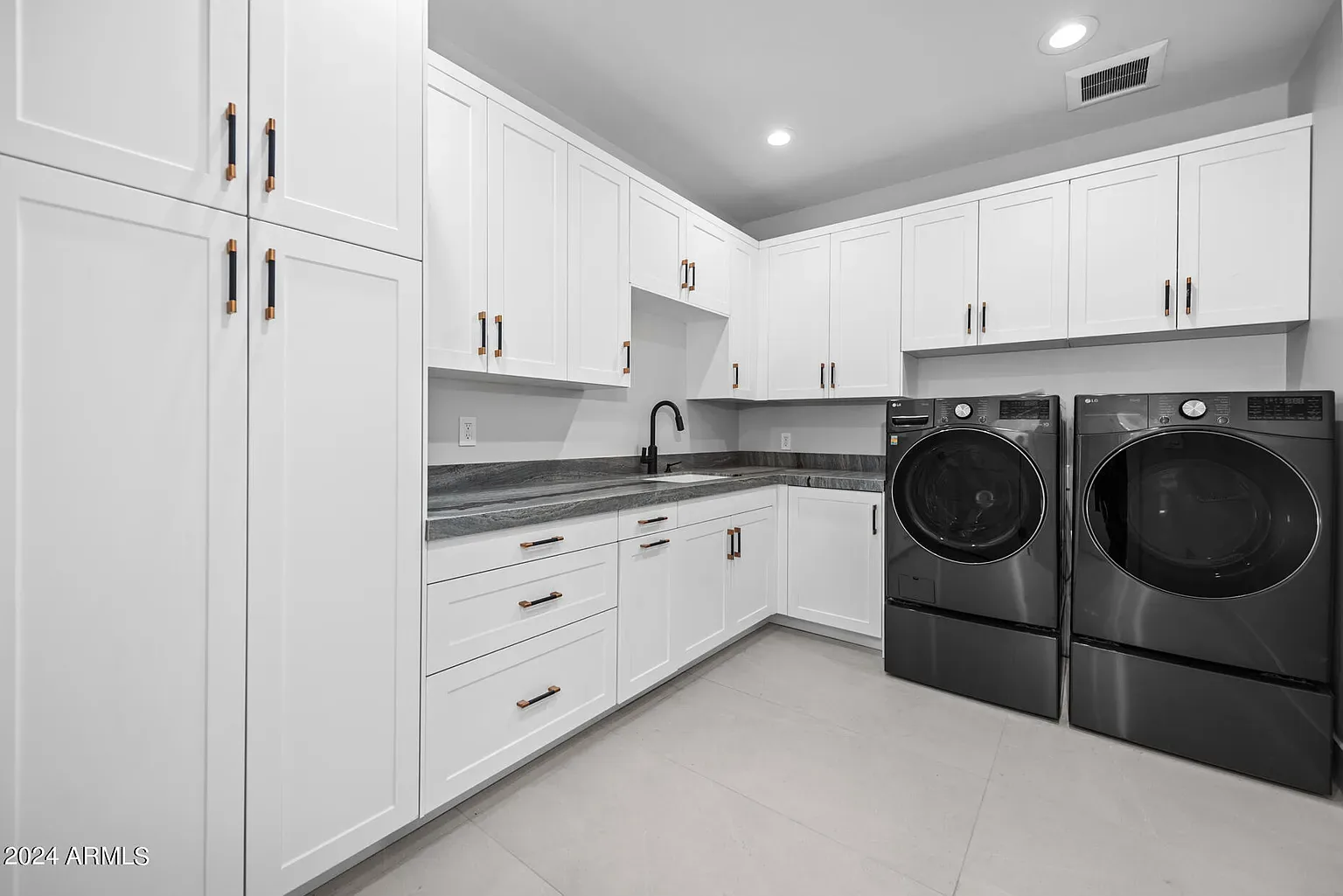 Laundry Room: Side-by-side laundry under a quartz folding counter, with upper cabinetry and a tiled surround.
