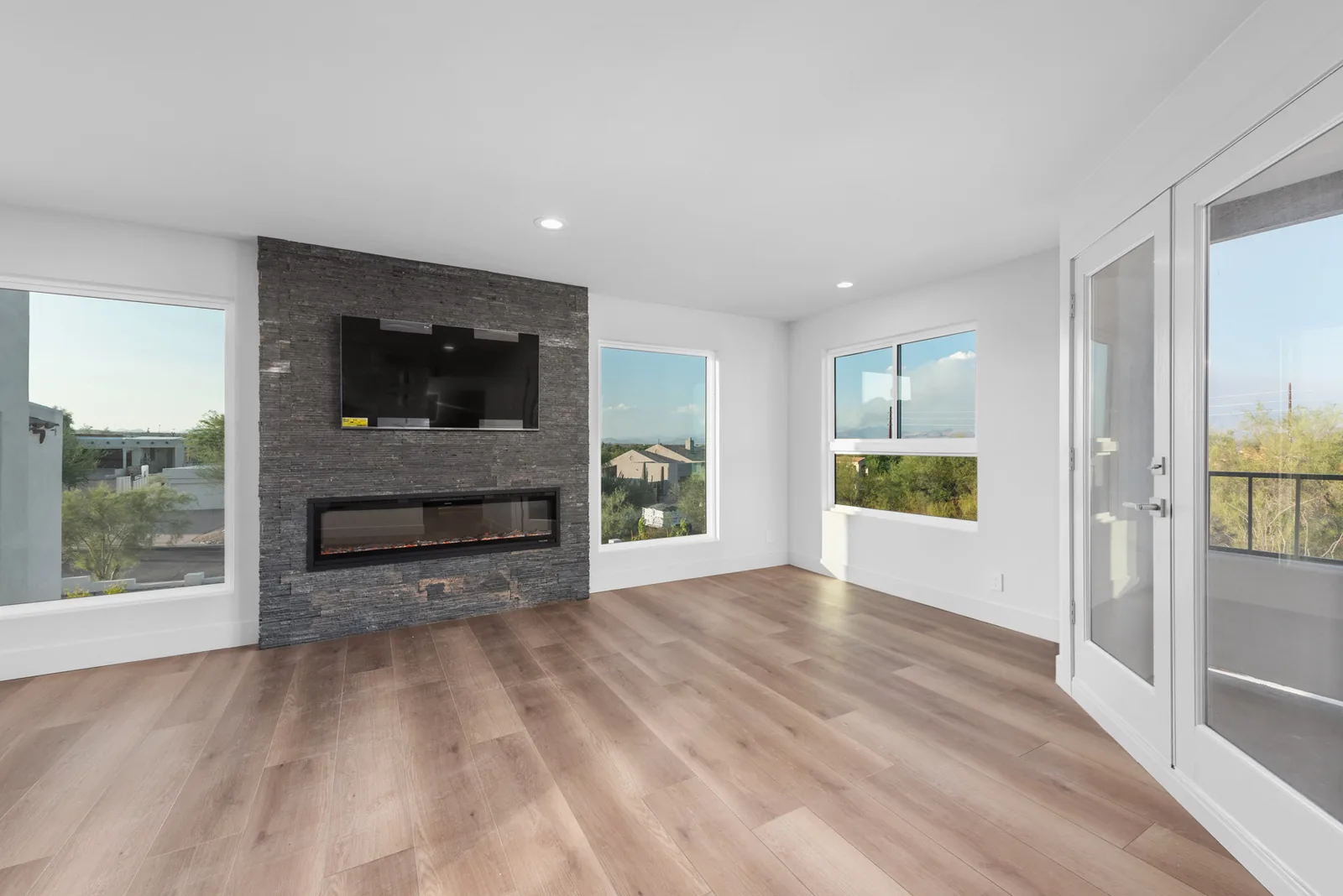 Linear Fireplace Living: Stacked-stone fireplace surround with a flush-mount television and continuous plank flooring.