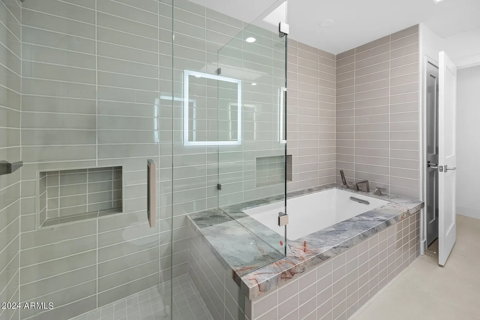 Spa Shower & Tub: Large-format porcelain wet area pairing a soaking tub with a walk-in shower and backlit mirror.