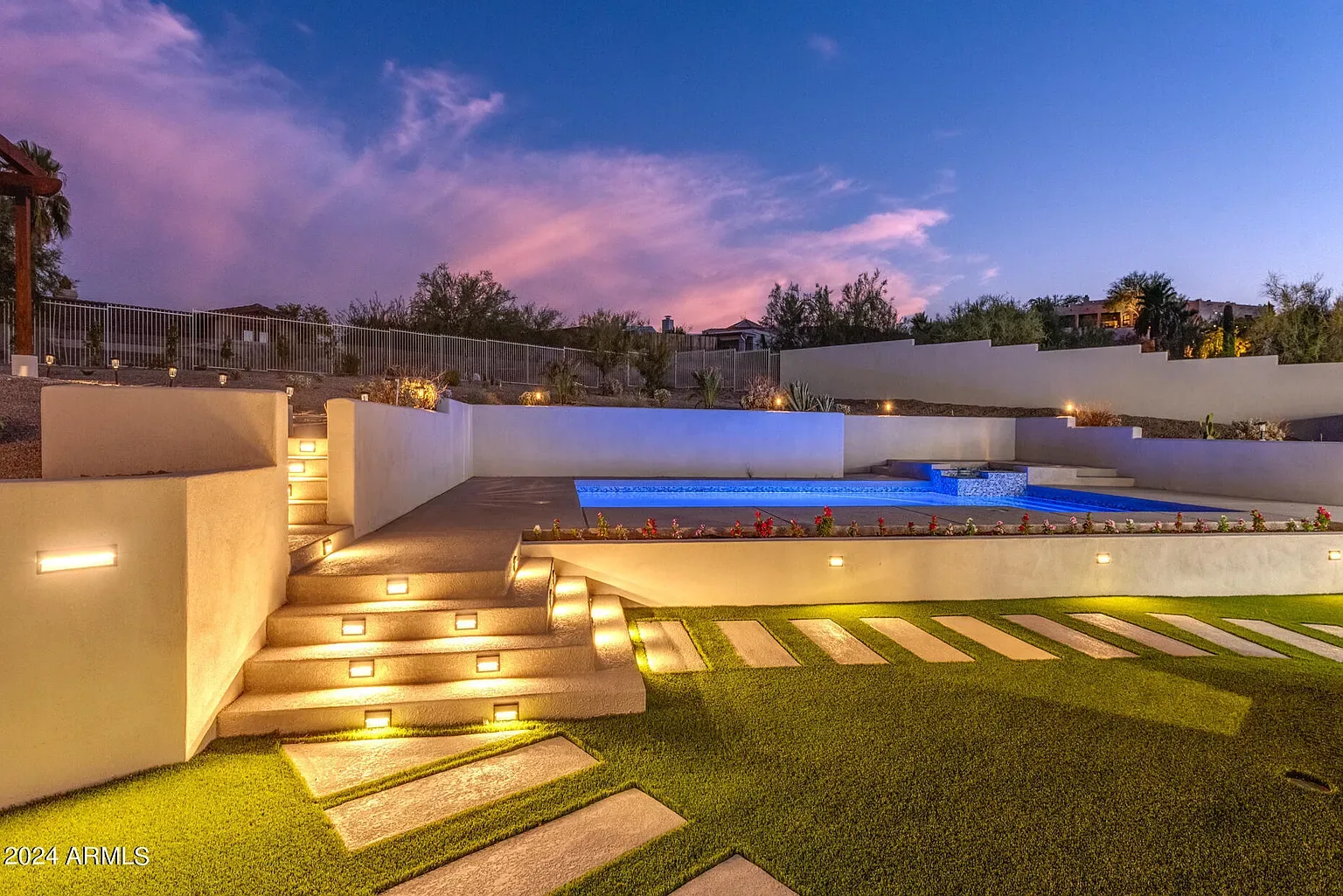 Twilight Pool Deck: Illuminated step lighting and a raised deck edge. Low-voltage runs coordinated in-house with the pool shell.